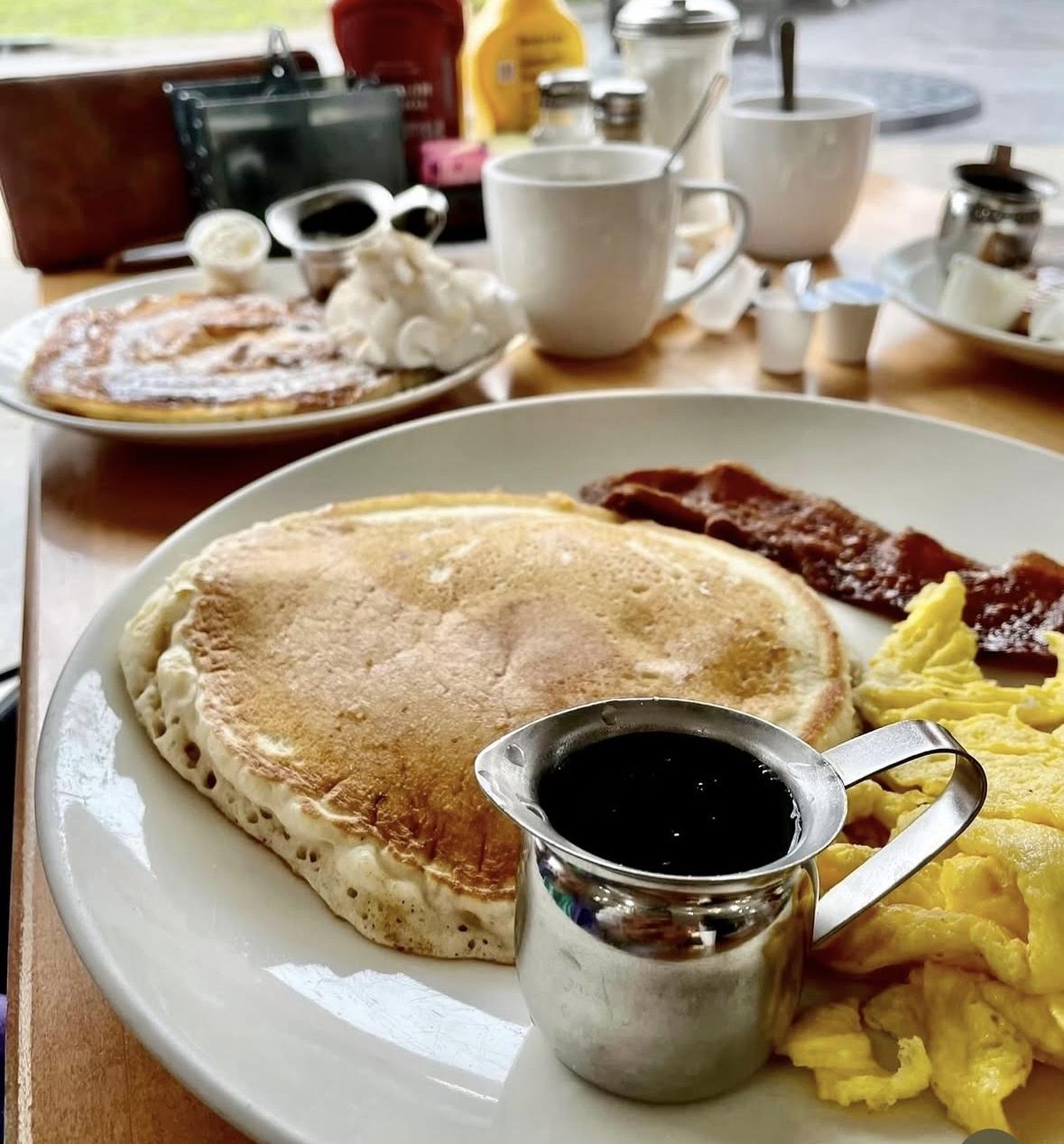 Pancakes, eggs, bacon, and coffee on a diner table